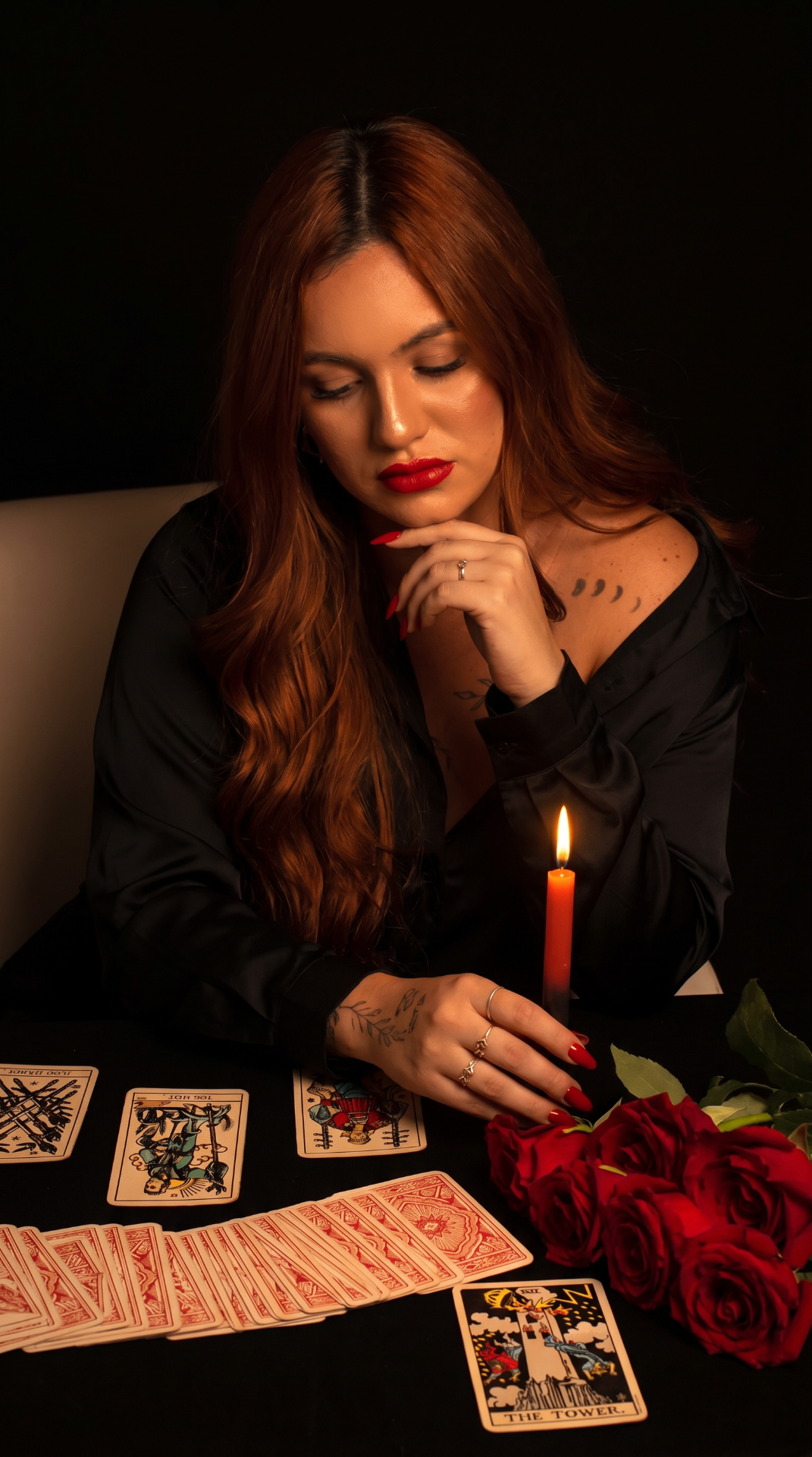 Taróloga em sessão à luz de velas com cartas de Tarot e rosas vermelhas